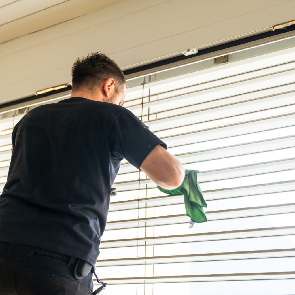House cleaner wiping window blinds
